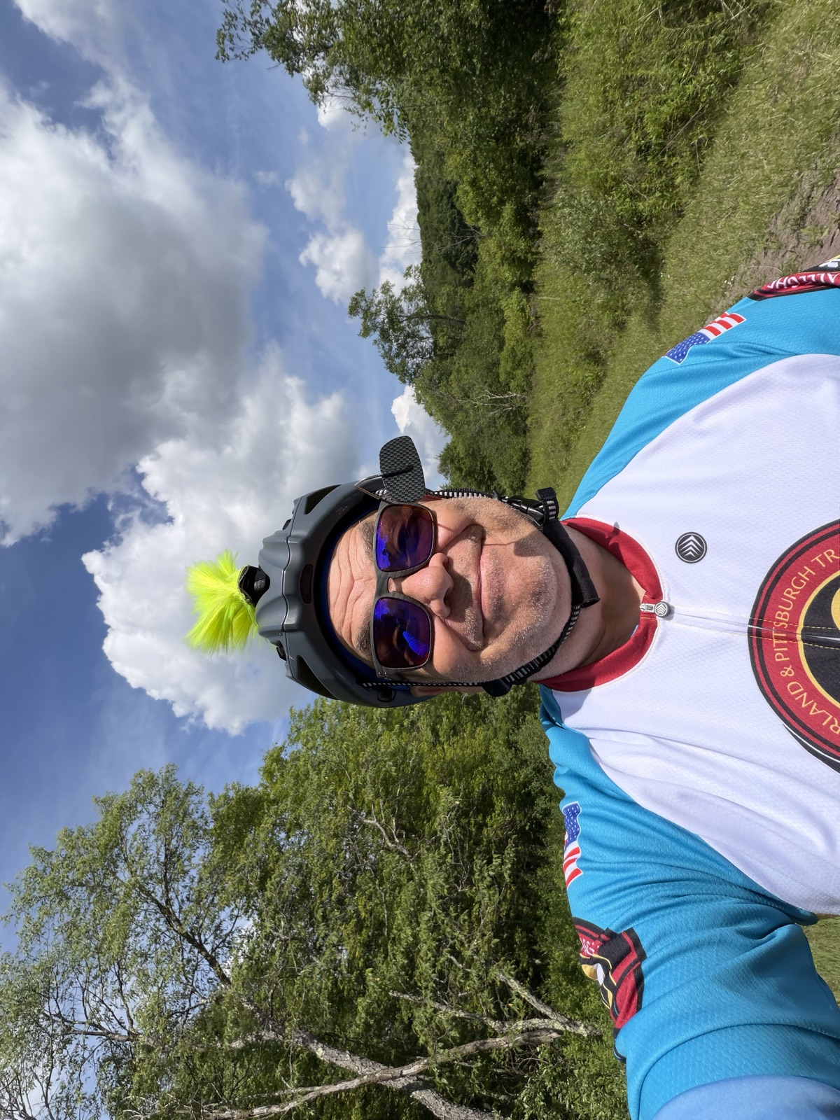Jim Cook on a rail-trail ride, grinning under a bike helmet with a neon-green mohawk